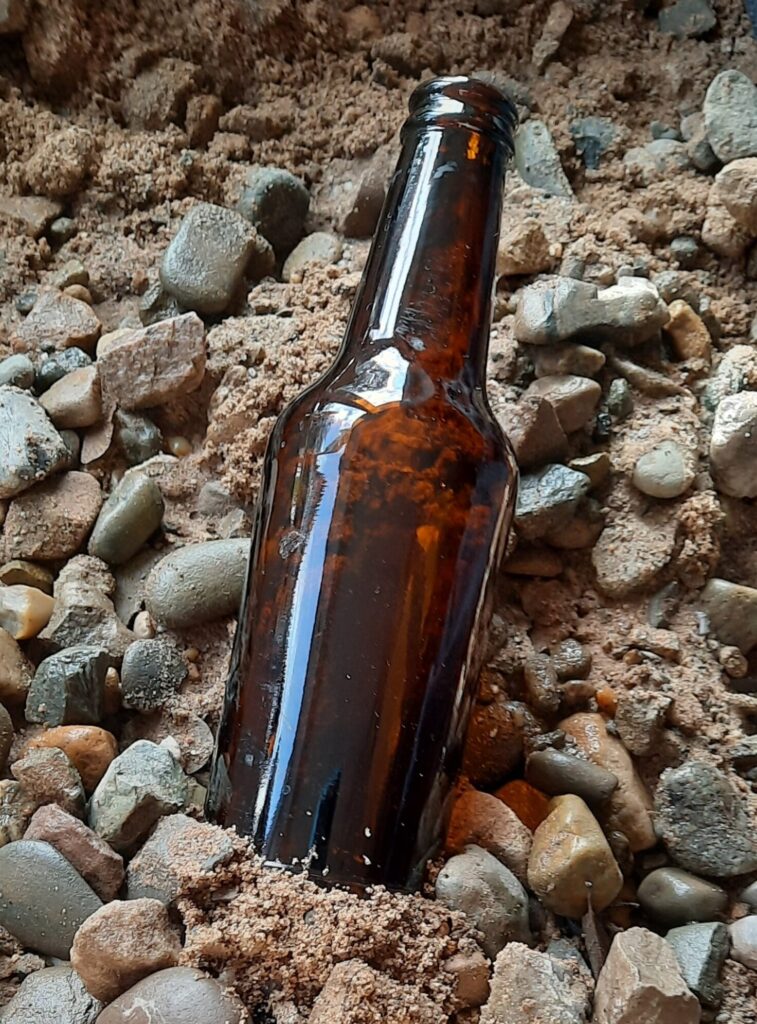 photograph by Gil Williams of a brown bottle on a pebble-sand beach