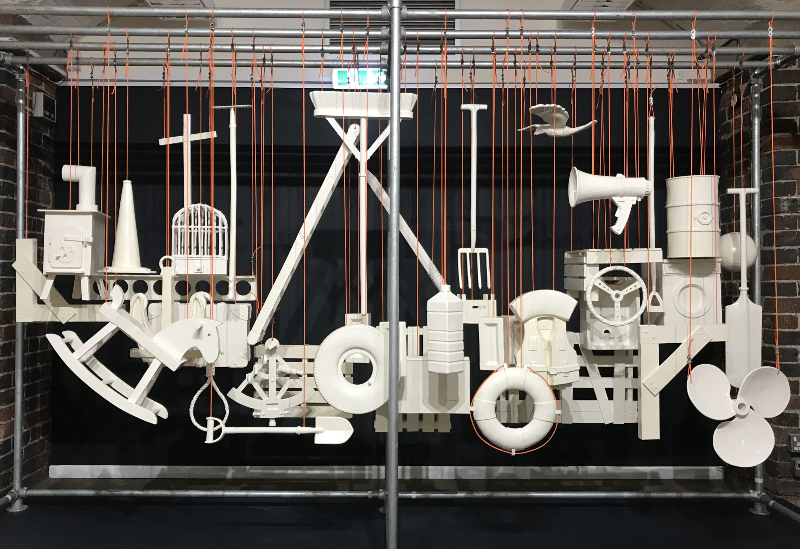 installation of individual household objects cast in white ceramic, suspended from orange ropes