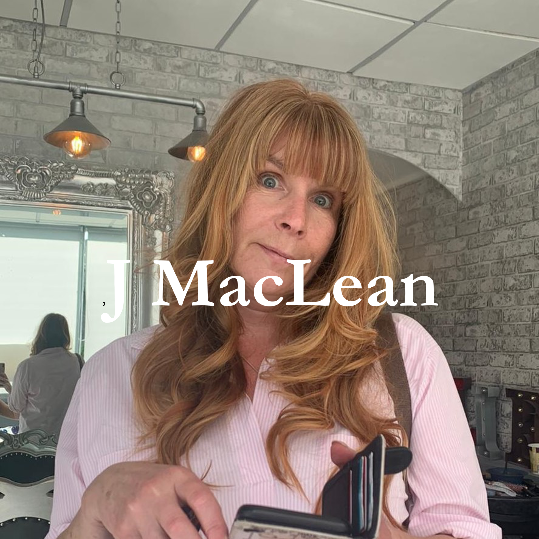 a woman with long light hair in a pink shirt, with her name - J MacLean - imposed over the top