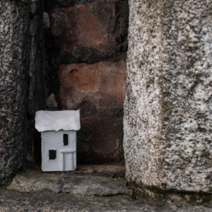 a small sculptural house sitting within a brick wall niche, looks like outside wall