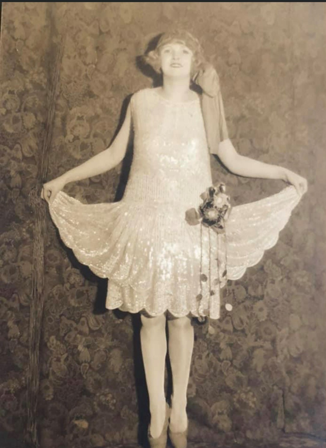 black and white photograph of a woman in a sparkling pale flapper dress with a sash around her hair